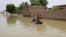 FILE - Young boys navigate a flooded street on a makeshift raft through the town of Salmaniya, about 25 miles (35 km) southwest of the capital, Khartoum, Sudan, Sept. 17, 2020. 