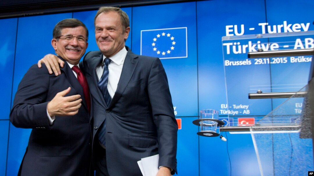 PM Turki Ahmet Davutoglu (kiri) berangkulan dengan Presiden Uni Eropa Donald Tusk pada KTT 4 jam di Brussels, Belgia Minggu (29/11).