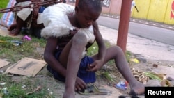 FILE - A homeless child repairs a shoe along a street in the in capital Kinshasa, in the Democratic Republic of Congo, June 2013.