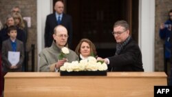 Canadian carpenter Michael Ibsen, left, a descendant of King Richard III, the last of the Plantagenet dynasty, and two other descendants place roses on the oak coffin with the remains of the monarch during a service in Leicester, England, March 22, 2015.