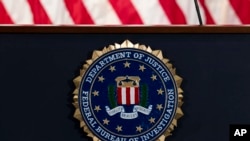 FILE - In this June 14, 2018, file photo, the FBI seal is seen before a news conference at FBI headquarters in Washington. The FBI is grappling with a seemingly endless cycle of money laundering schemes that law enforcement officials say they’re…