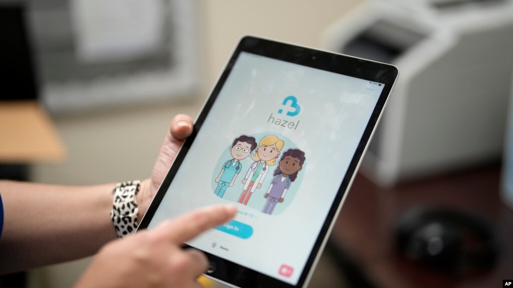 An employee of Hazel Health displays the opening page of the company's app, which allows Miami-Dade County public school students to receive telehealth therapy services, on World Mental Health Day, Oct. 10, 2023, at Miami Arts Studio, a public 6th-12th grade magnet school.