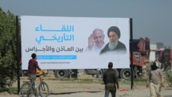 Iraqis walk by a poster announcing the upcoming visit of Pope Francis and his planned meeting with prominent Shiite Muslim leader, Ayatollah Ali al-Sistani, in Najaf, Iraq, March 3, 2021.