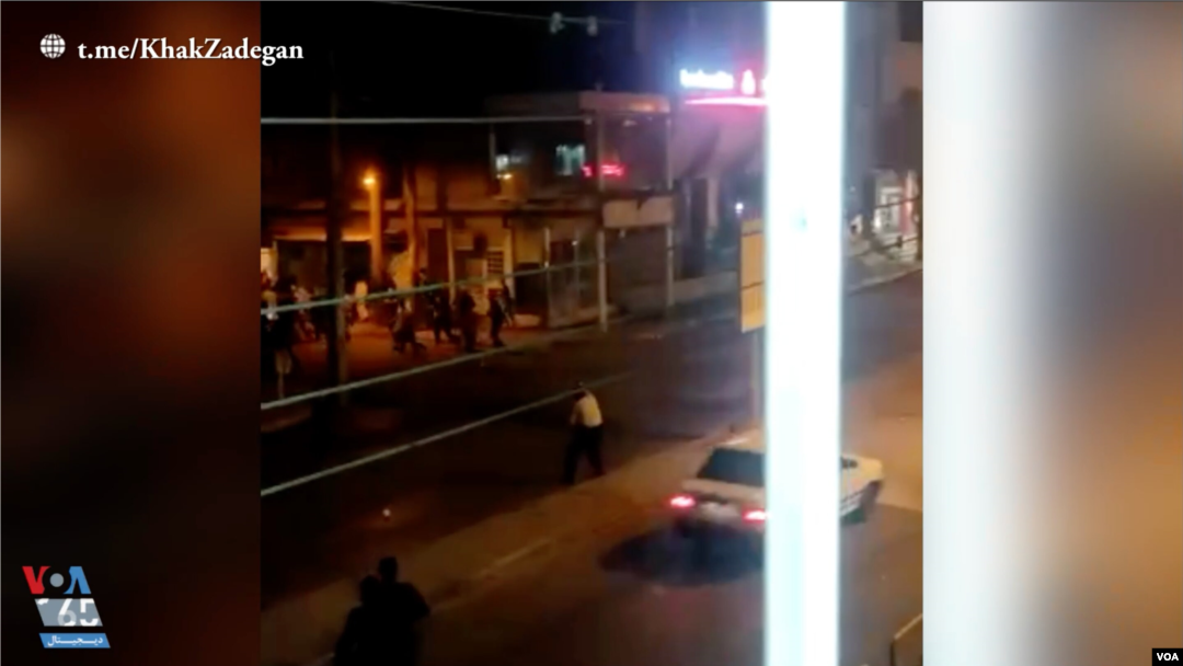 In this screen grab of a video shared on social media and vetted by the Associated Press, an Iranian policeman apparently stands in the street in Susangerd after firing in the air toward protesters who run away from him on July 18, 2021. 