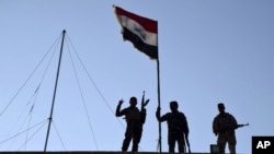 FILE - Iraqi soldiers plant the national flag over a government building in Ramadi, Dec. 21, 2015.