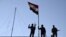 FILE - Iraqi soldiers plant the national flag over a government building in Ramadi, Dec. 21, 2015.