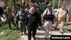 Iraq Prime Minister Haider al-Abadi, center, smiles as he leaving the operations centre outside Fallujah, Iraq, June 1, 2016.