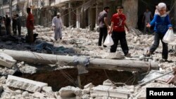 A girl gestures as she walks on the rubble of collapsed buildings at a site hit by what activists said was a barrel bomb dropped by forces loyal to Syria's President Bashar al-Assad in Aleppo's district of al-Sukari, June 17, 2014. 