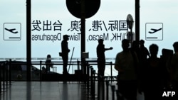 资料照片：一名安保人员在北京国际机场引导旅客。(2025年7月6日)