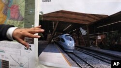 FILE - Rogelio Jiménez Pons, director of Fonatur, points to photos of a planned train through the Yucatan Peninsula, during an interview in Mexico City, March 18, 2019. 