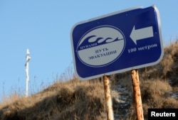 A direction sign reading "Tsunami. Evacuation route. 100 meters" is pictured in front of a cross in the village of Malokurilskoye on the island of Shikotan, Russia, Dec. 18, 2016.