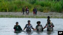 Migrantes haitianos vadean el río Tuquesa después de caminar por el Tapón del Darién, el miércoles 4 de octubre de 2023, en Bajo Chiquito, Panamá. 