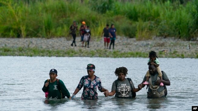 Migrantes haitianos vadean el río Tuquesa después de caminar por el Tapón del Darién, el miércoles 4 de octubre de 2023, en Bajo Chiquito, Panamá. 