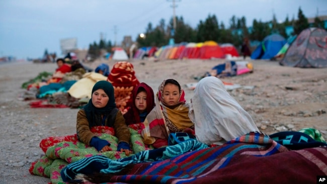 FILE - Afghan children are covered with a blanket as their families camp outside the Directorate of Disaster, in Herat, Afghanistan, Nov. 29, 2021.