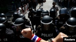 An anti-government protester gestures towards riot police outside the headquarters of the ruling Puea Thai Party of Prime Minister Yingluck Shinawatra in Bangkok, Nov. 29, 2013.