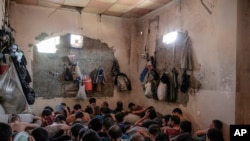FILE - In this July 18, 2017 file photo, Suspected Islamic State members sit inside a small room in a prison south of Mosul, Iraq. 