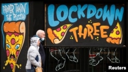 People walk past a mural on the windows of a closed pizza restaurant amid the outbreak of the coronavirus disease in Manchester, Britain, Feb. 22, 2021. 
