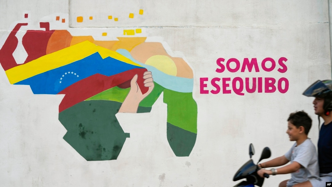 Un niño conduce una motocicleta frente a un mural del mapa venezolano con el territorio Esequibo incluido en el barrio 23 de Enero de Caracas, Venezuela, el lunes 11 de diciembre de 2023.