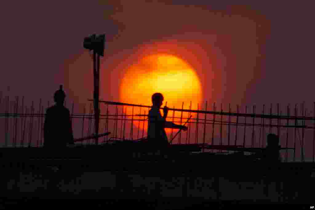 Pakistani laborers work on a bridge as the sun sets in Islamabad.