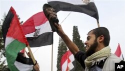 A Palestinian protester holds a shoe as others wave Palestinian and Egyptian flags during a demonstration calling for the removal of Egyptian President Hosni Mubarak in Gaza City, Feb 3, 2011