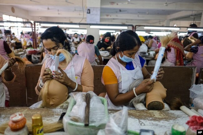 Workers set hair on mannequins at a factory inside an export processing zone in Mongla, Bangladesh, March 3, 2022. (AP Photo/Mahmud Hossain Opu)
