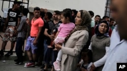 Immigrants wait outside a police station to receive temporary traveling papers at Kos island, Greece, May 27, 2015. 