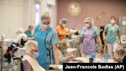 Nurses give food during lunch at a nursing home in Kaysesberg, eastern France on Monday Dec. 21, 2020. (AP Photo/Jean-Francois Badias)