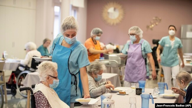 Nurses give food during lunch at a nursing home in Kaysesberg, eastern France on Monday Dec. 21, 2020. (AP Photo/Jean-Francois Badias)