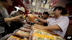 FILE - A vendor, right, sells mooncakes to a customer, left, at a shop in Shanghai, China. 