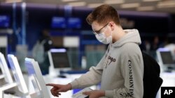 New York University student Hector Medrano, of Los Angeles, checks in for his flight using a touchscreen Saturday, March 14, 2020, at jetBlue's terminal in John F. Kennedy International Airport in New York.
