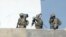 Members of the Tunisian military walk on a balcony during an operation against gunmen in the town of Oued Ellil near the Tunisian capital Tunis, Oct. 24, 2014. 