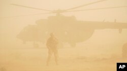 A Russian soldier stands guard as a military helicopter takes off at an airport in Deir eI-Zor, Syria, Sept. 15, 2017.