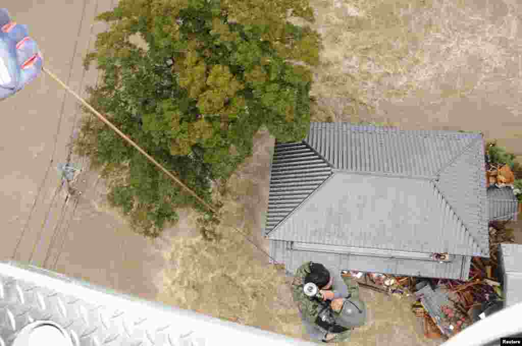 A resident is rescued by a Japan Self-Defense Force (JSDF) helicopter over a residential area flooded by the Kinugawa River, after typhoon Etau struck, in Joso, Ibaraki prefecture, Japan, Sept. 10, 2015.