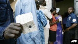 Un homme montre sa carte d'électeur à l'extérieur d'un bureau de vote dans la capitale Yaoundé le 11 octobre 2004.