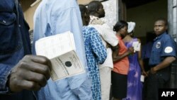 Un homme montre sa carte d'électeur à l'extérieur d'un bureau de vote dans la capitale Yaoundé, le 11 octobre 2004.