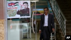 A Palestinian customer walks out of a shawarma restaurant with a poster of North Korean leader Jim Jong at the entrance of it in Jebaliya refugee camp, Gaza Strip, Dec. 14, 2017. 