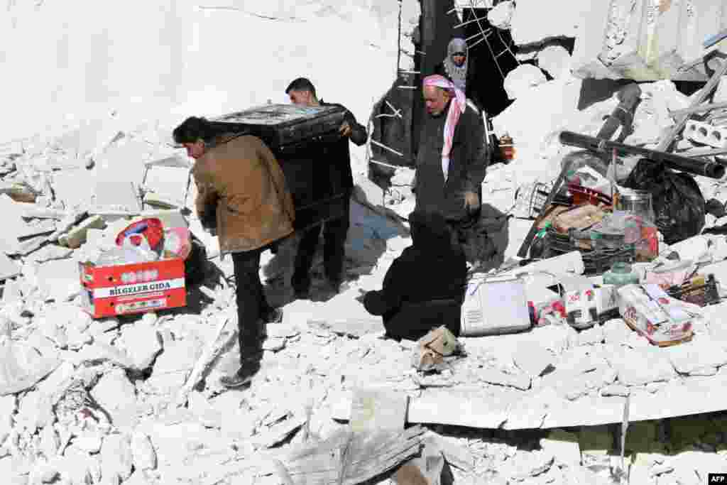 People take a gas stove out of a damaged building following air strikes in the northern city of Aleppo, Syria, as the heavy casualty toll from the strikes has sparked a mass exodus.