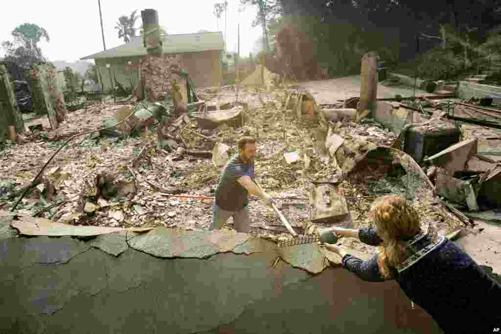 Paul Mattesich hands a jar to his wife Erica Mattesich while sifting through rubble at his family&#39;s home in Ventura following a wildfire, Dec. 6, 2017.