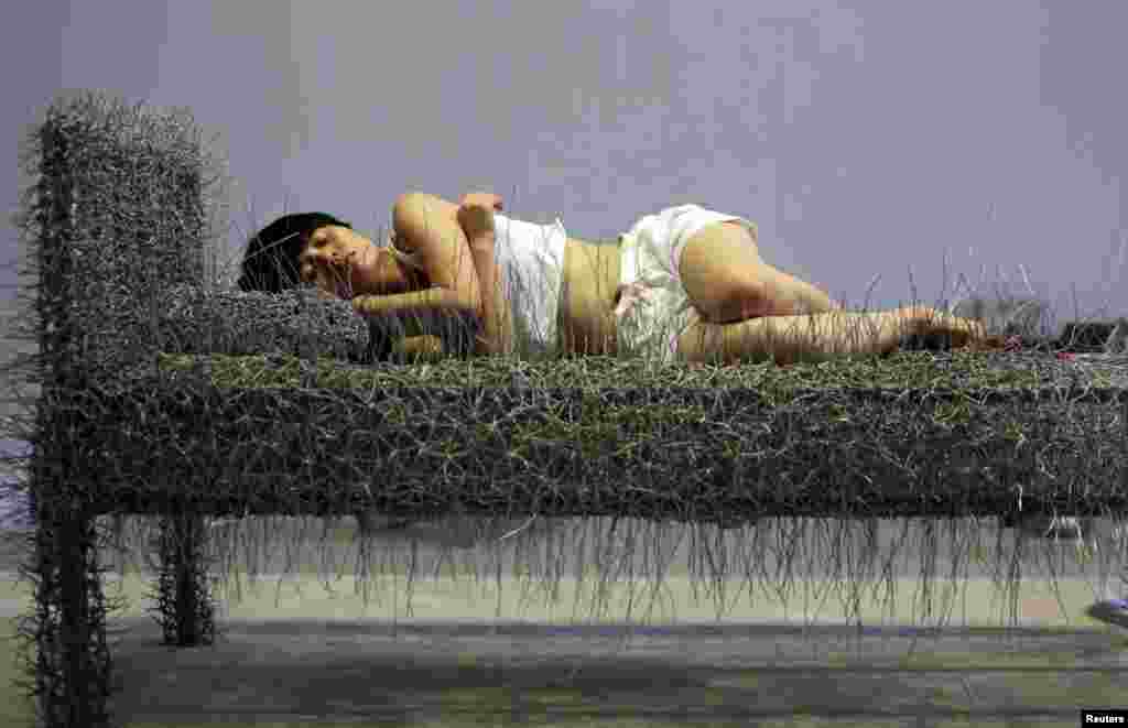 Chinese artist Zhou Jie takes a nap on an unfinished iron wire bed, one of her sculpture works, after lunch at Beijing Now Art Gallery, China.