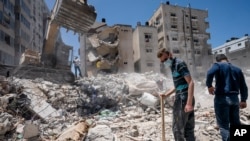 Peralatan berat digunakan untuk membersihkan puing-puing bangunan yang hancur akibat serangan udara Israeli di Kota Gaza sebelum gencatan senjata mengakhiri konflik senjata antara Gaza dan Israel, 27 Mei 2021.