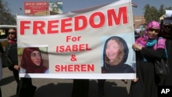 FILE - Yemeni activists held a banner with pictures of kidnapped French Isabelle Prime (r) and her Yemeni colleague during a protest for their release in Sanaa, Yemen, March 5, 2015.