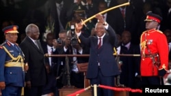 Kenya's President Uhuru Kenyatta (C) displays the special sword that he received to represent his instruments of power from his predecessor, Mwai Kibaki (2nd L), after his official swearing-in ceremony at Kasarani Stadium in Nairobi, April 9, 2013.