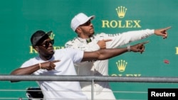 Pembalap Mercedes, Lewis Hamilton dari Inggris berpose dengan juara lari cepat Olimpiade Usain Bolt setelah Hamilton memenangkan Grand Prix AS di Sirkuit Americas. (Foto: Jerome Miron-USA TODAY Sports via Reuters) 