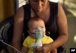 La migrante hondureña Janet Zuniga sostiene a su hijo Linder de cinco meses de edad, mientras recibe tratamiento médico fuera de un refugio, el lunes 26 de noviembre de 2018, en Tijuana, México.
