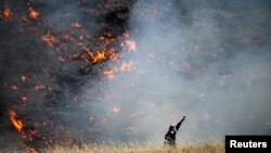 A firefighter reacts during a wildfire near the village of Metochi, north of Athens, Greece, Aug. 14, 2017.
