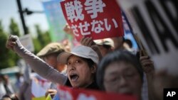 Hundreds of people stage a rally outside the Japanese Prime Minister’s Office in Tokyo, May 14, 2015, protesting a set of controversial bills intended to expand Japan’s defense role at home and internationally. A banner, top, reads "No War."