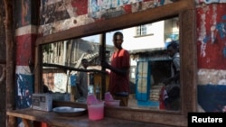 FILE - Pedestrians are reflected in the mirror of a street barber shop in Freetown, Sierra Leone.