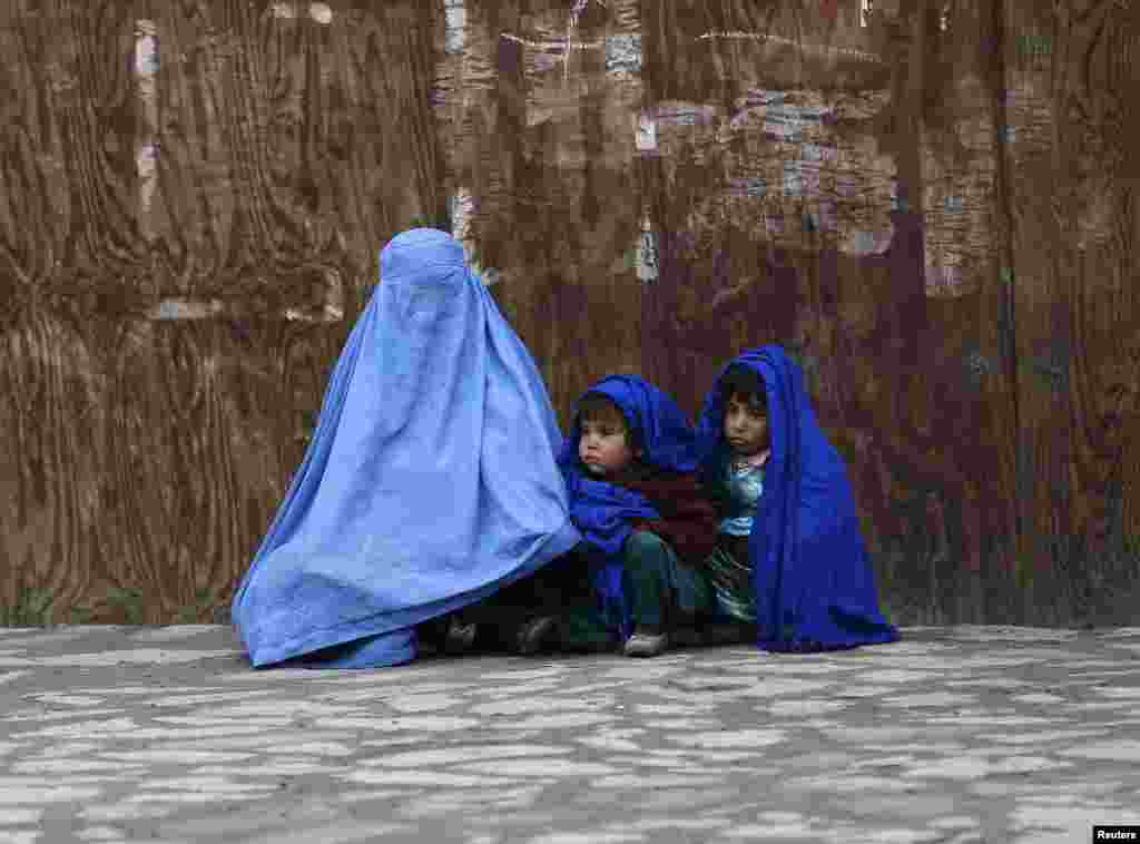 An Afghan woman waits for transportation with her children on a cold day in Kabul.