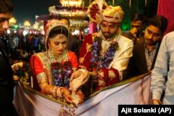 Sepasang pengantin melakukan ritual saat pernikahan massal di Surat, India, Minggu, 24 Desember 2017. (Foto: AP/Ajit Solanki)
