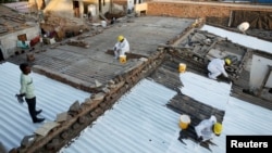 Painters apply liquid-applied membrane coating that, according to the authorities, helps bring down the temperature inside the shanties at a slum in Ahmedabad, India, Jan. 30, 2025. 